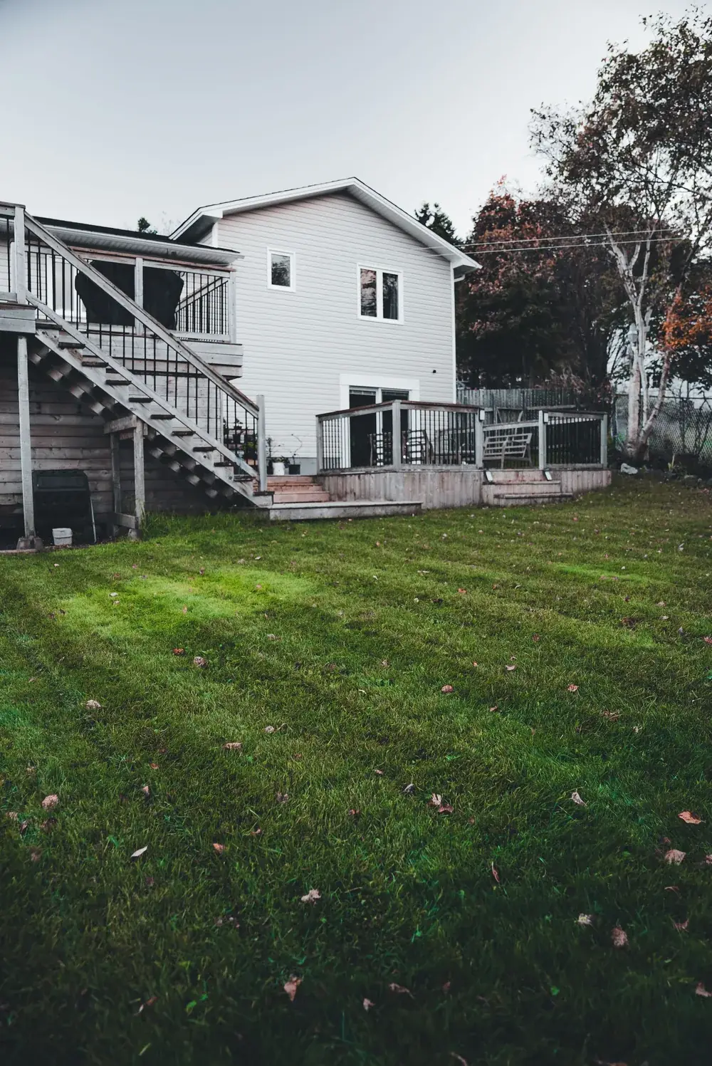 Backyard of a two-story home with a wooden deck and stairs